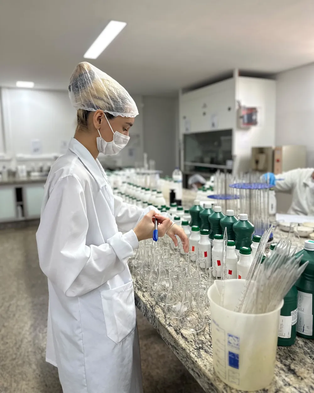 Analista da Conágua Ambiental preparando frascos Erlenmeyer para a análise de amostras de água no laboratório